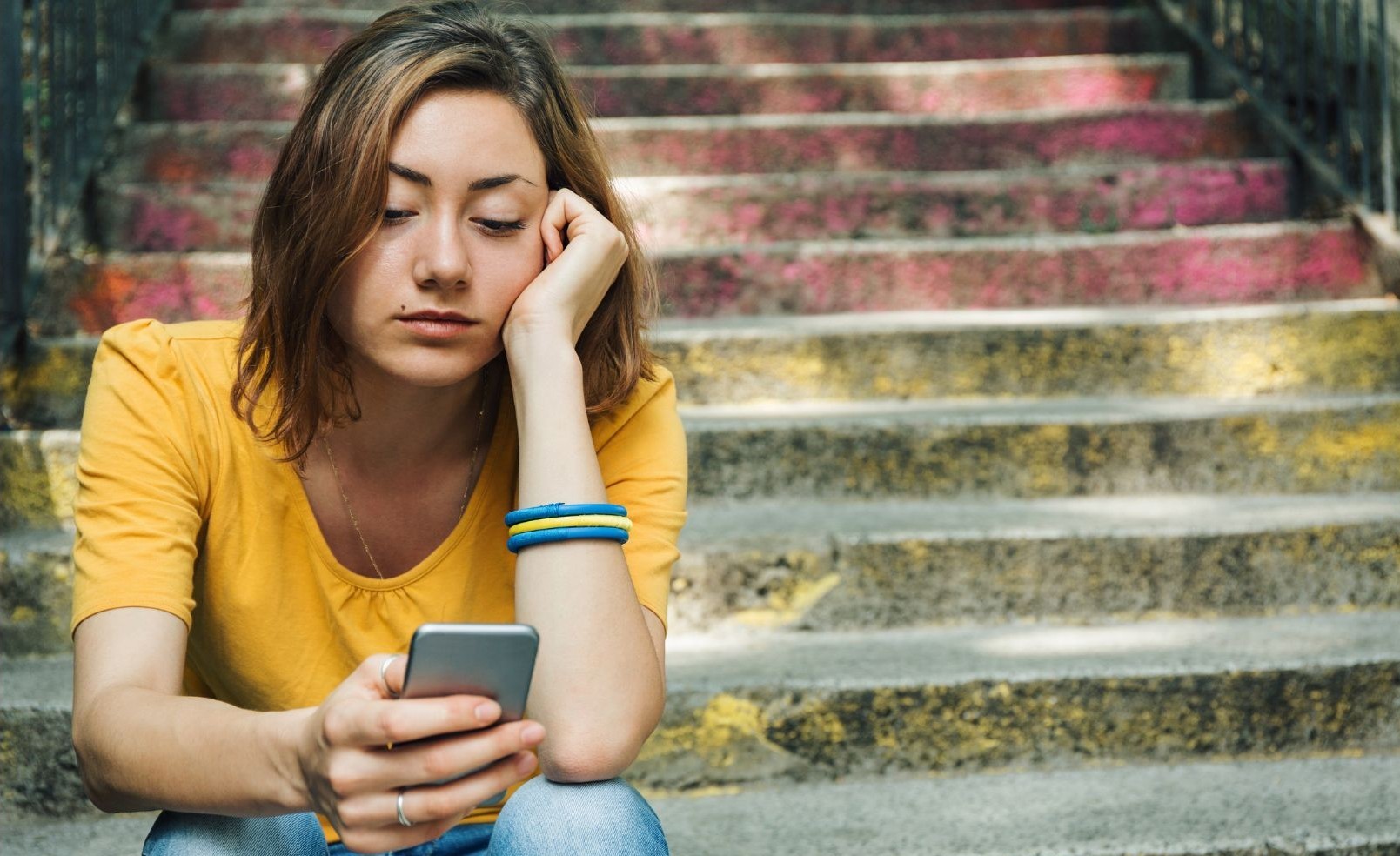 dziewczyna siedzi na schodach i patrzy w smartfona